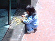 Child plays with drinking straws in the street